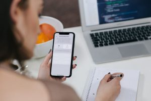 Photo of woman examining a mobile phone and making notes