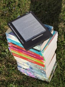 ereader placed on top of a pile of printed books