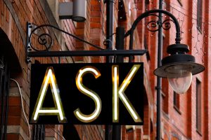 Street sign with the word "ASK" lit up under a lamp