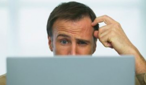 Man scratching his head in confusion at a computer screen