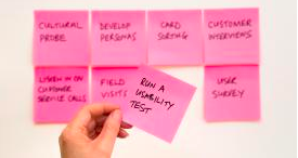 A collection of pink sticky notes being positioned on a board