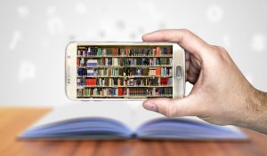 Smart phine being held up with a picture of book shelves which take up the whole screen