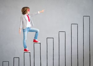 Image of a young boy walking up the bars of a hand drawn black and white bar chart with his left arm out stretched.