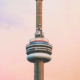 The top section of the CN Tower against a pink sky