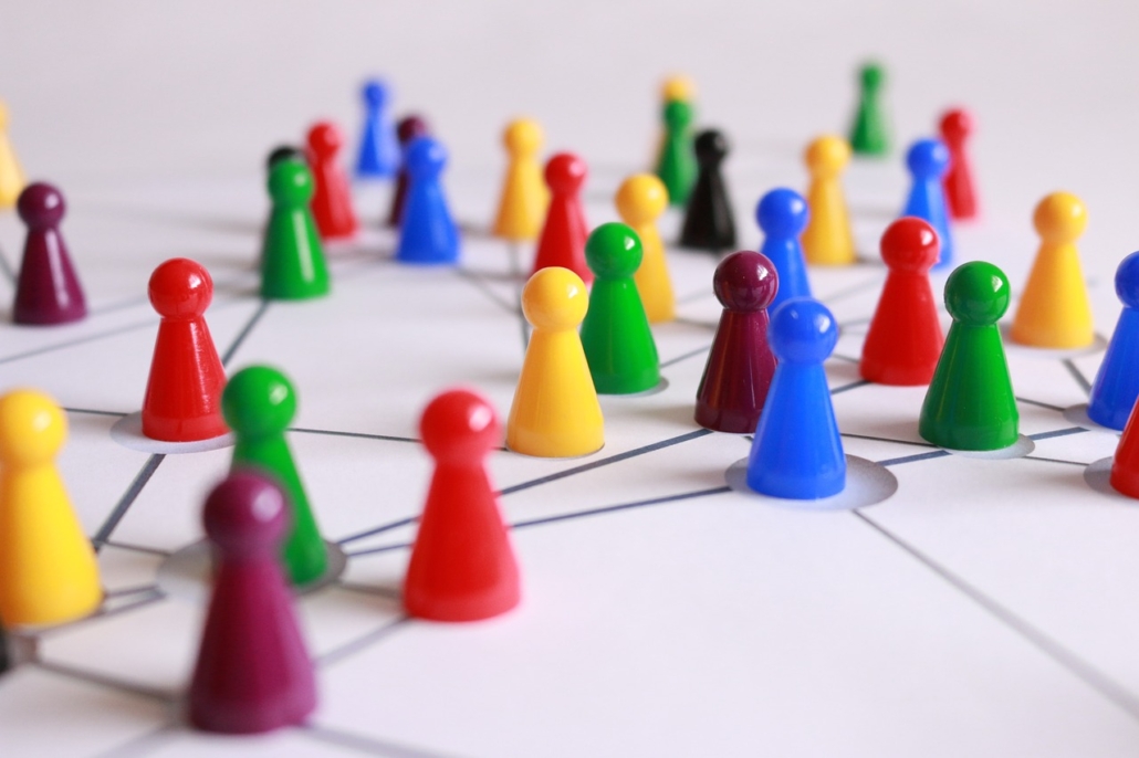 various coloured cone shaped game piece are connected by lines drawn on qhite paper to denote the concept of networking