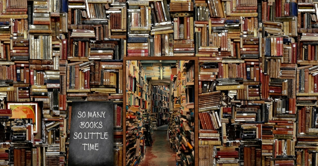 A wall of books at varying angles with  a mirror reflecting a corridor of books opposite. A chalkboard sign reads "So Many books, so little time" reflecting the enormity of the task.