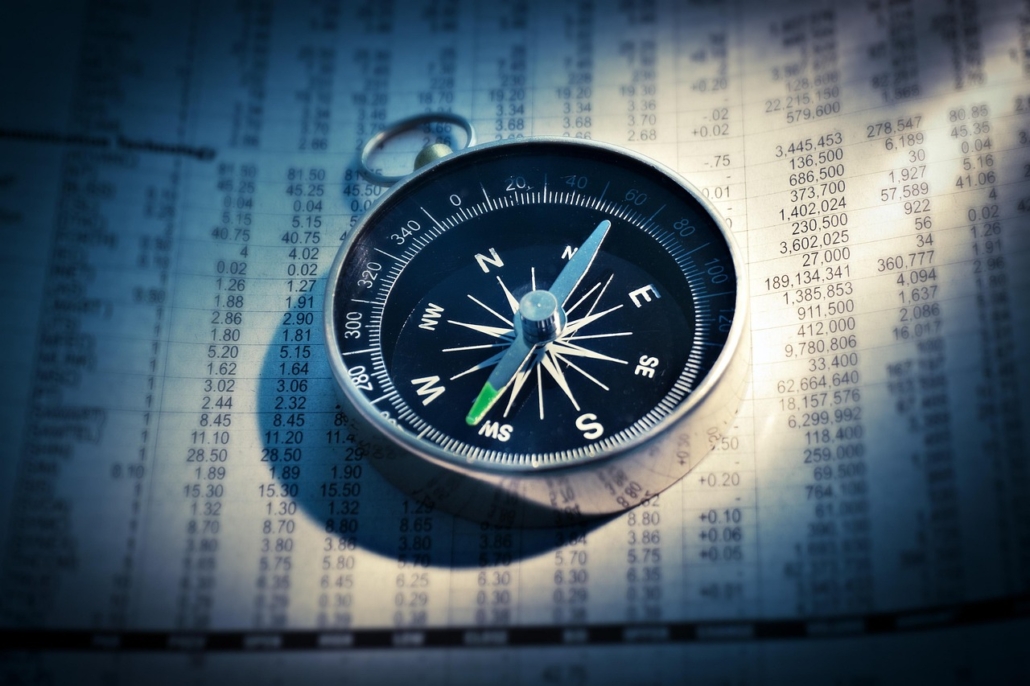 A traditional compass atop a newspaper article full of data indicating guidance
