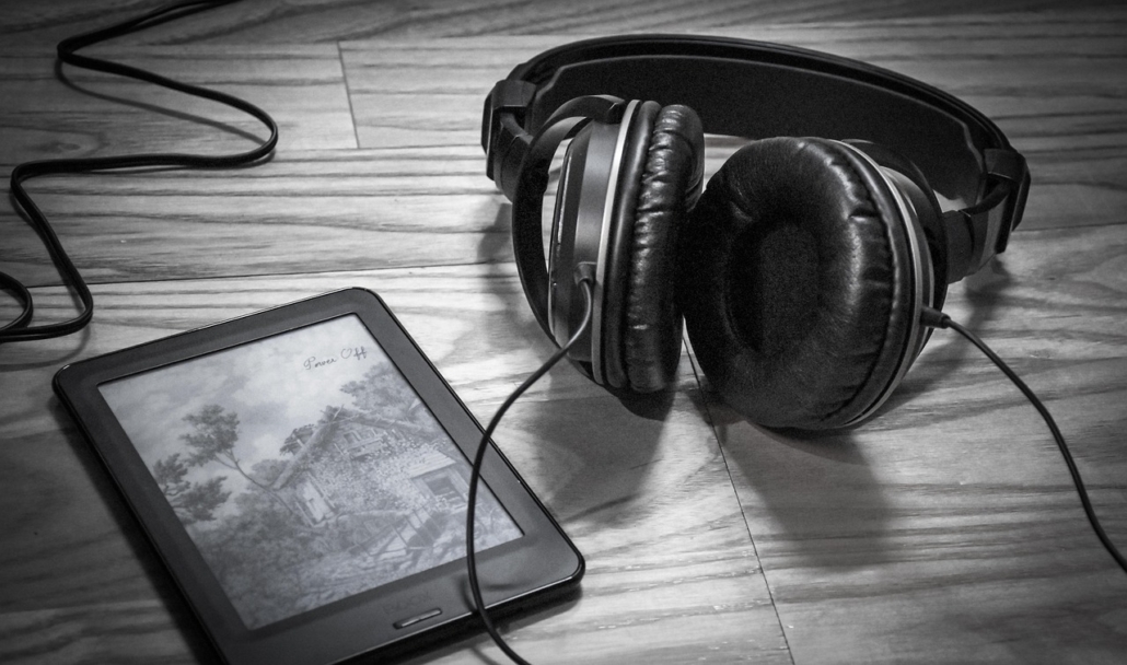 an ereader placed on a table with a pair of headphones attached